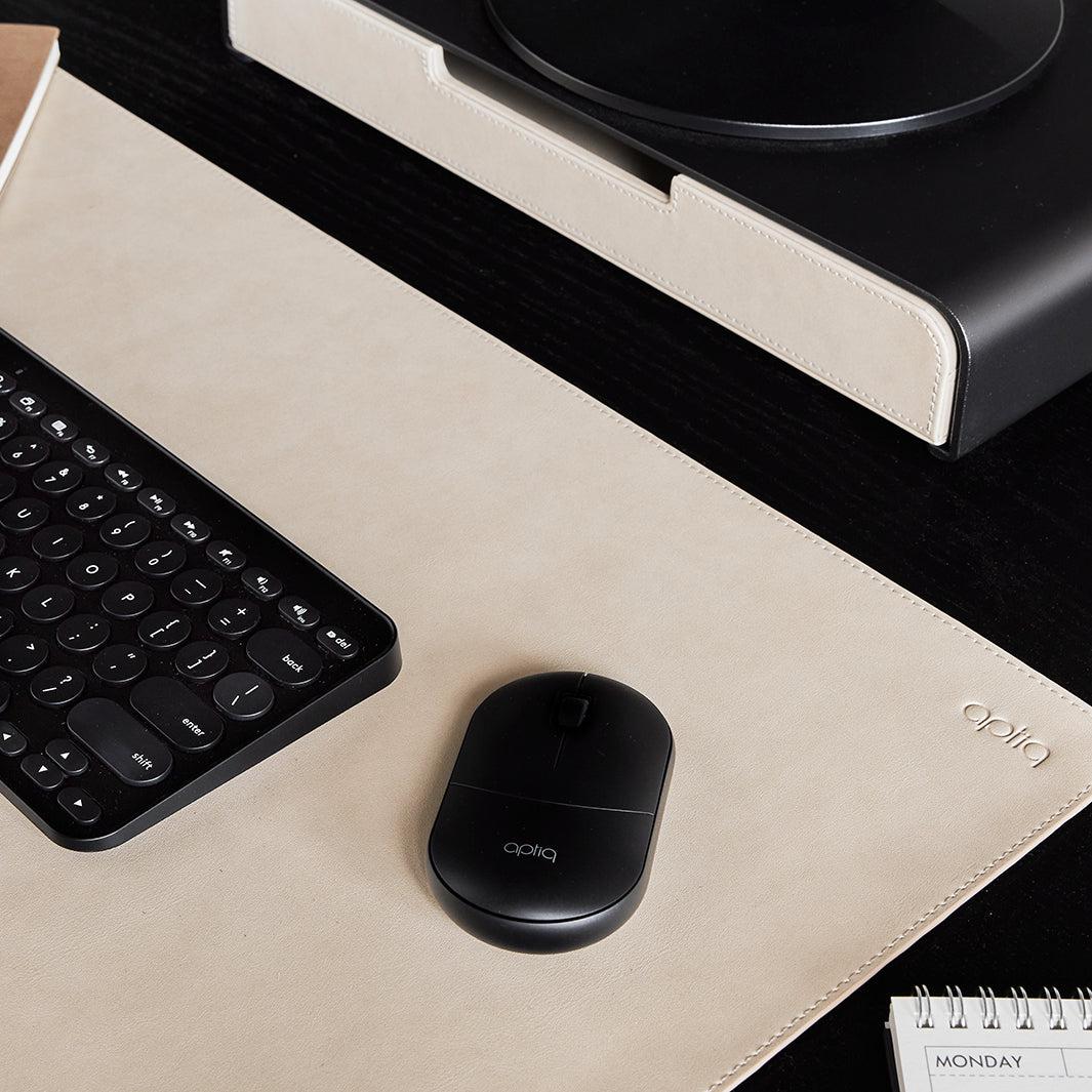 Close-up van een zwarte Aptiq muis op een sand kleurige bureau onderlegger met zwart toetsenbord