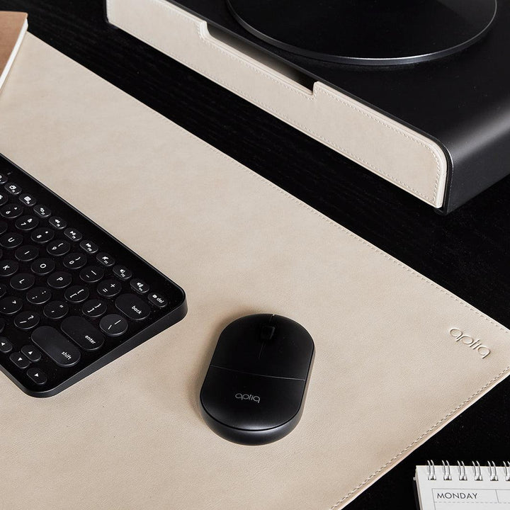 Close-up van een zwarte Aptiq muis op een sand kleurige bureau onderlegger met zwart toetsenbord