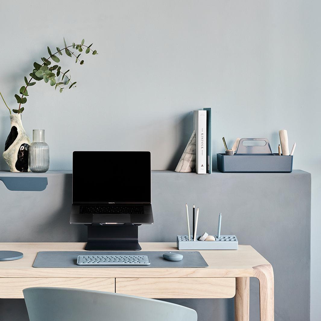 Werkplek set met een laptopstandaard en bijpassende stijlvolle accessoires in blauw op een licht eiken bureau