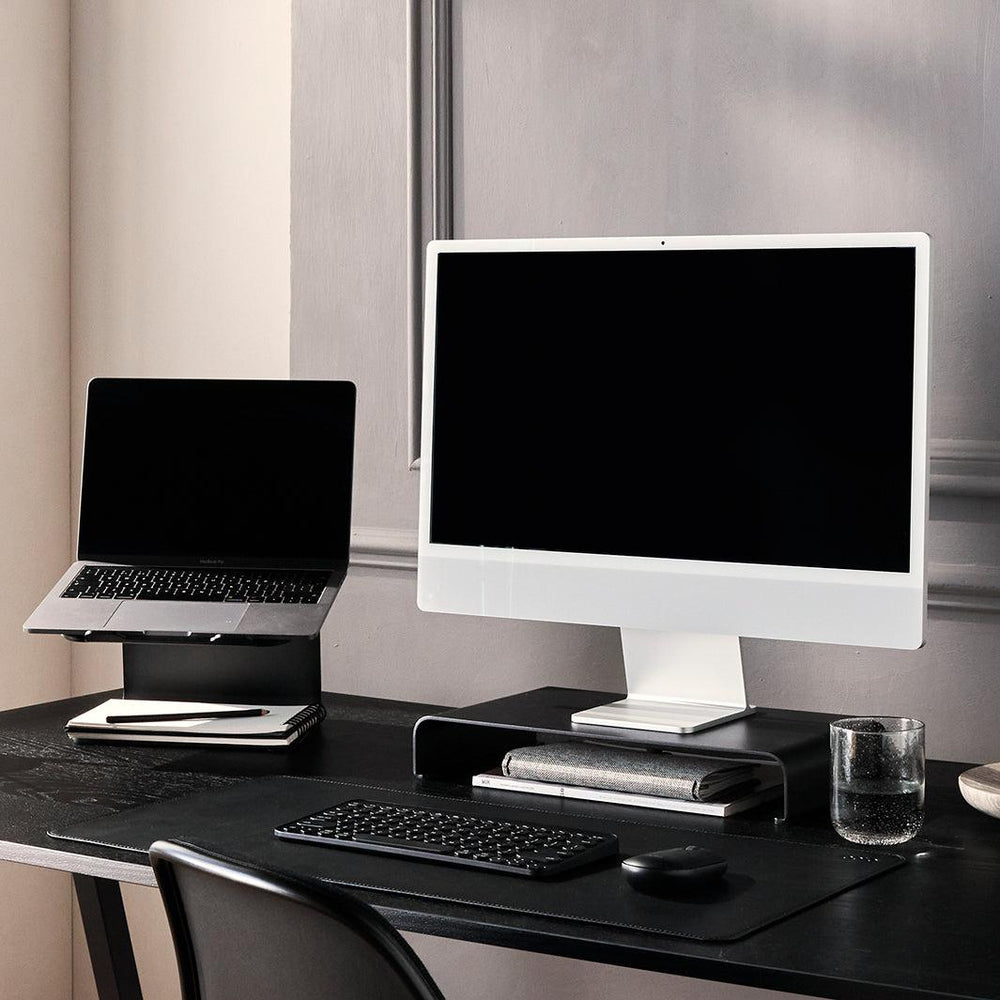 Werkplek met monitor en laptop met zwarte bureau accessoires