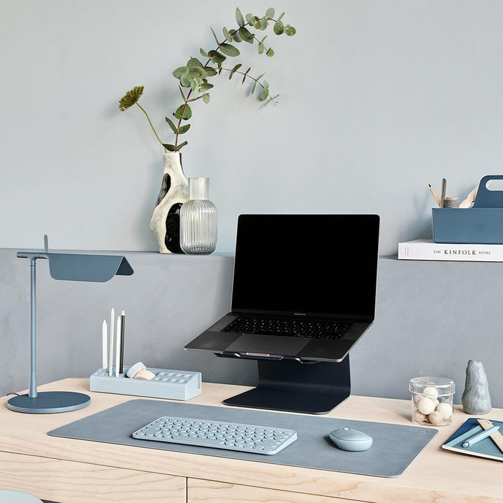 Werkplek set met laptop toetsenbord, muis en onderlegger in blauw tinten op een licht eiken bureau