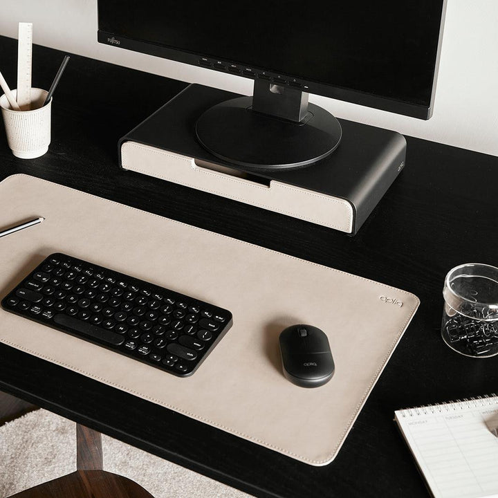 Werkplek van boven bekeken met een monitor op een zwarte standaard met een organizer lade in de kleur sand met bijpassende bureau accessoires