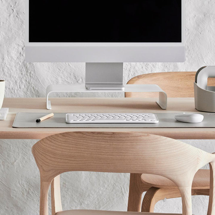 Close-up van een witte monitor standaard met witte bureau accessoires en onderlegger in de kleur stone