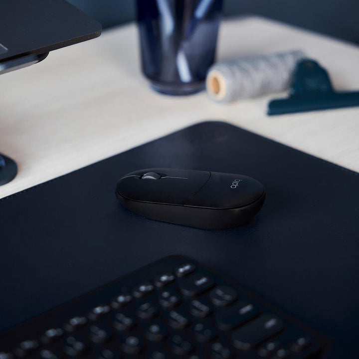 Close-up van een zwarte design muis op een bureau onderlegger in de kleur midnight blue