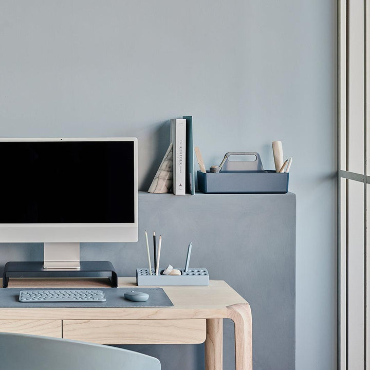 Werklek met een witte monitor op een baluwe standaard met bijpassende bureau accessoires en blauw toetsenbord en muis