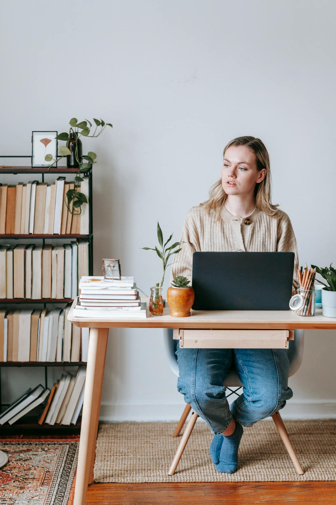 Vrouw zit achter laptop te werken en kijkt opzij