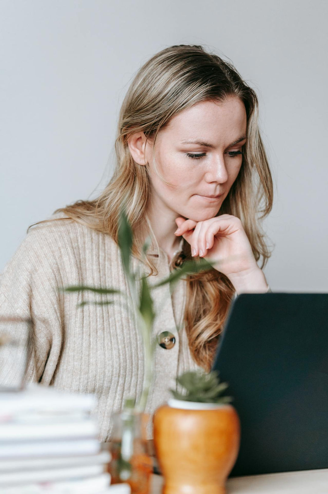 Vrouw zit achter laptop te werken en kijkt aandachtig naar haar scherm