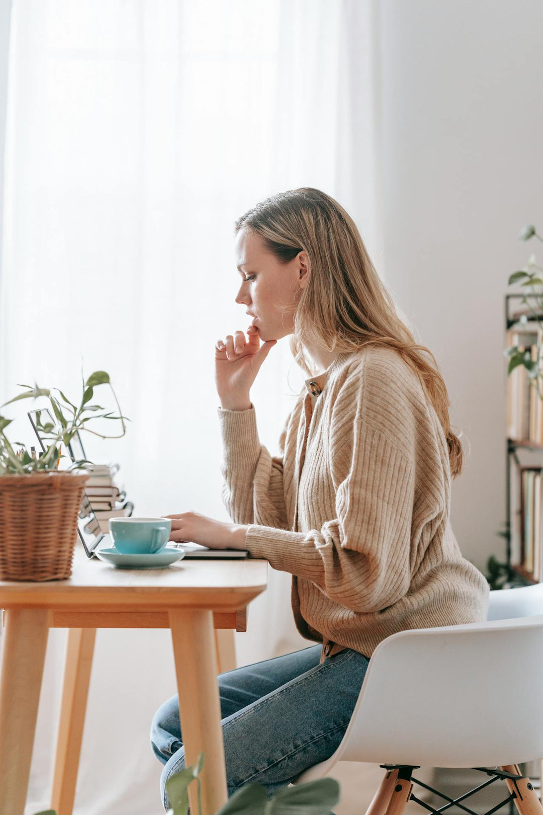 Vrouw zit achter laptop te werken aan tafel van de zijkant gezien